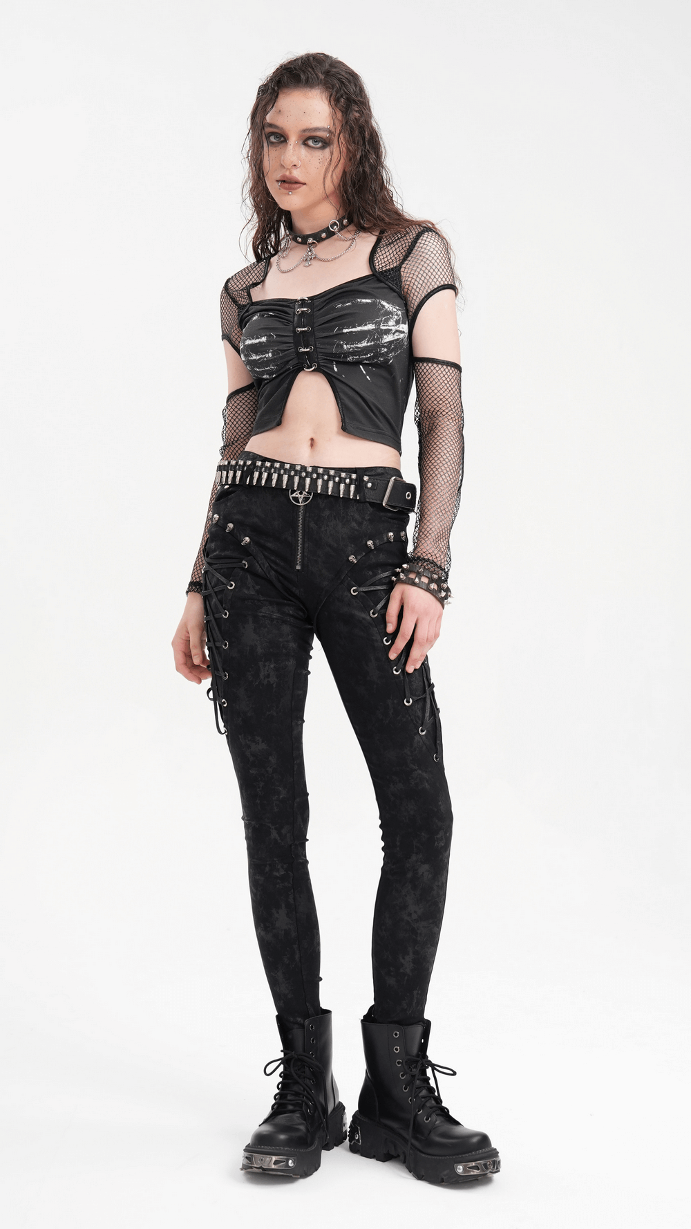 Edgy model in black mesh top and punk skinny pants with chains and combat boots, showcasing alternative gothic fashion style.