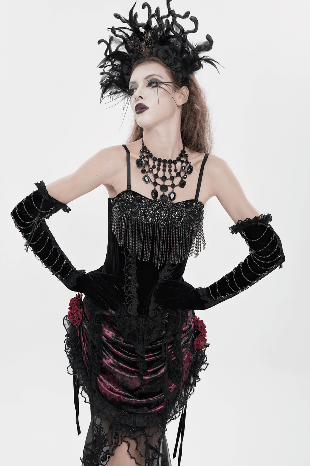 Alt Tag: Black Gothic Lace-Up Velvet Fringe Corset Top worn with dramatic black headpiece, layered necklace, and lace skirt on white background