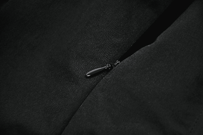 Close-up of the zip detail on a Black Gothic Lace Up Zip Front Pleated Mini Dress, featuring a sleek black zipper.