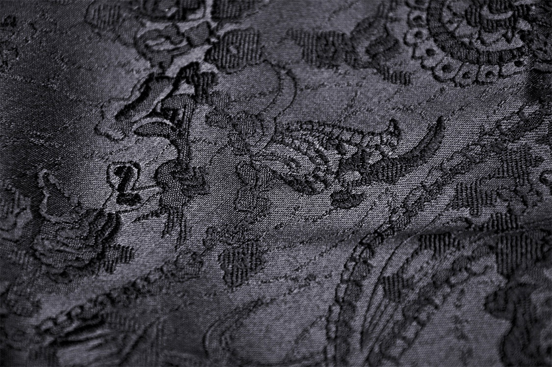 Close-up of intricate black lace fabric with elegant floral and swirled patterns.