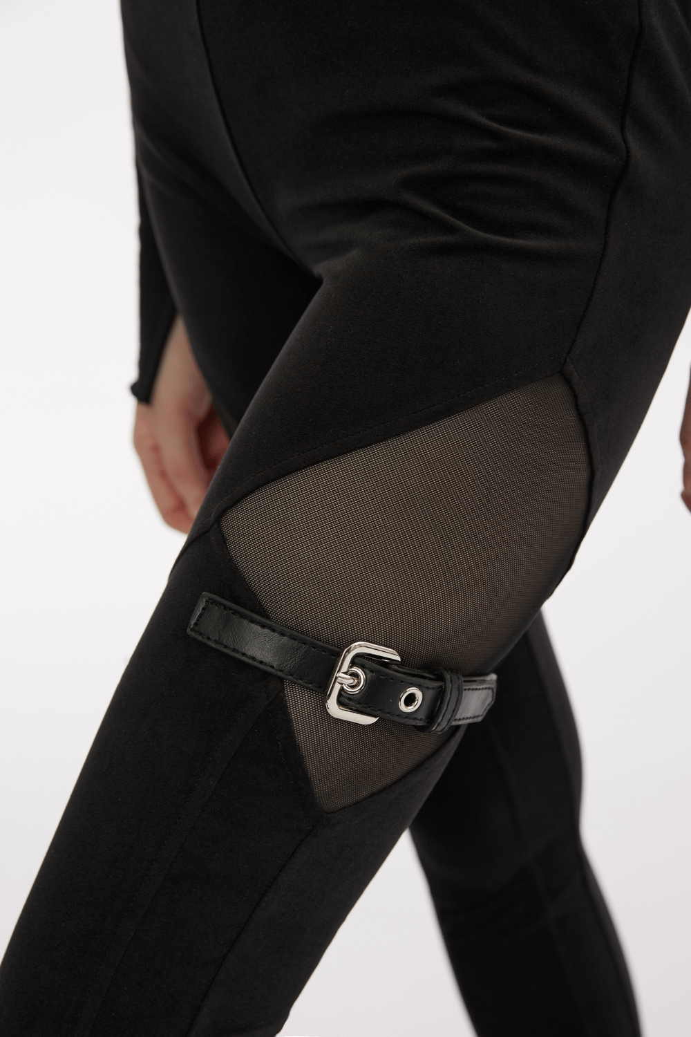 Close-up of black gothic leggings with mesh panels and buckle accents, perfect for a punk-inspired look.