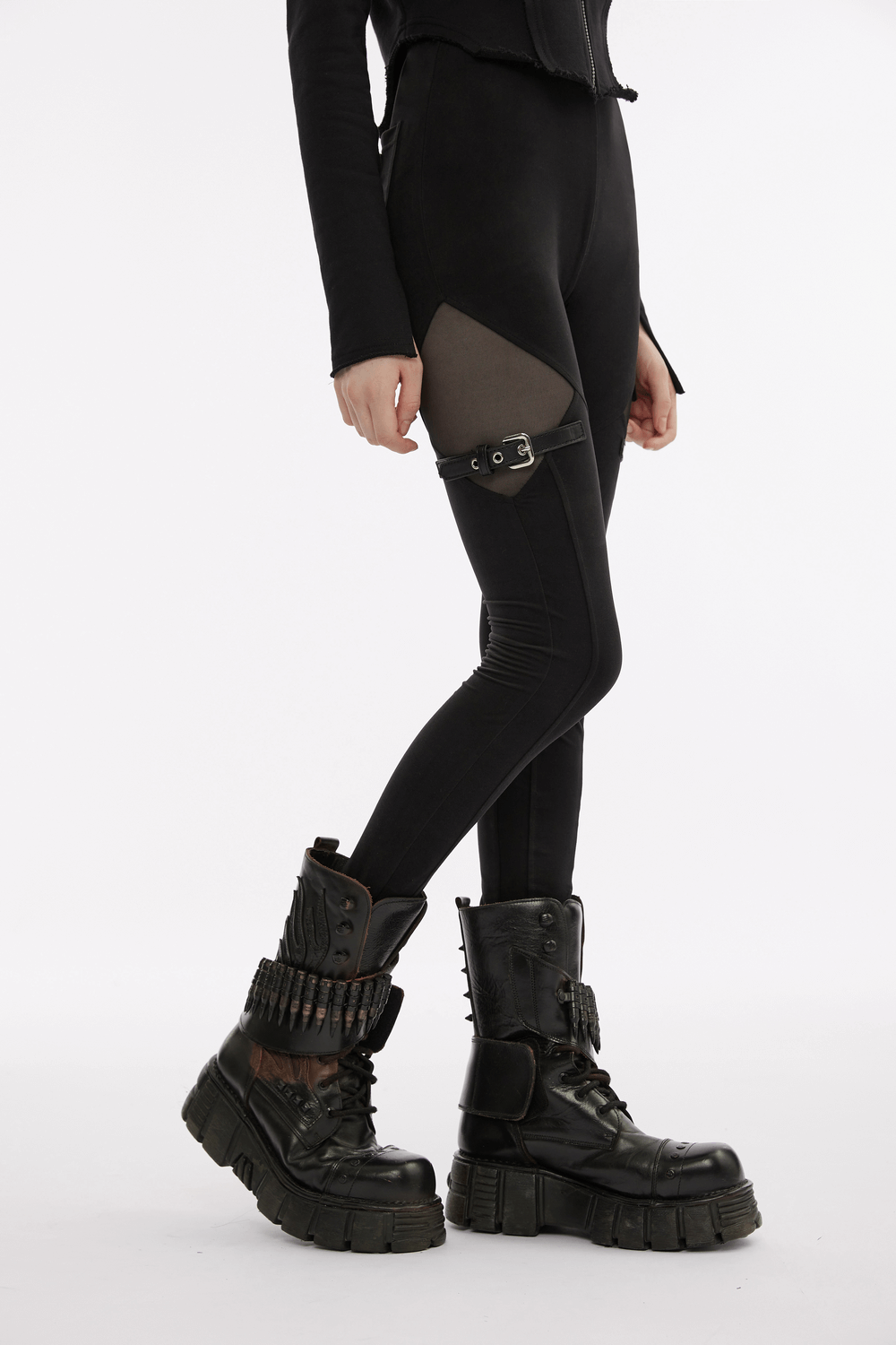 Black gothic leggings with mesh panels and buckle accents, paired with edgy black combat boots.