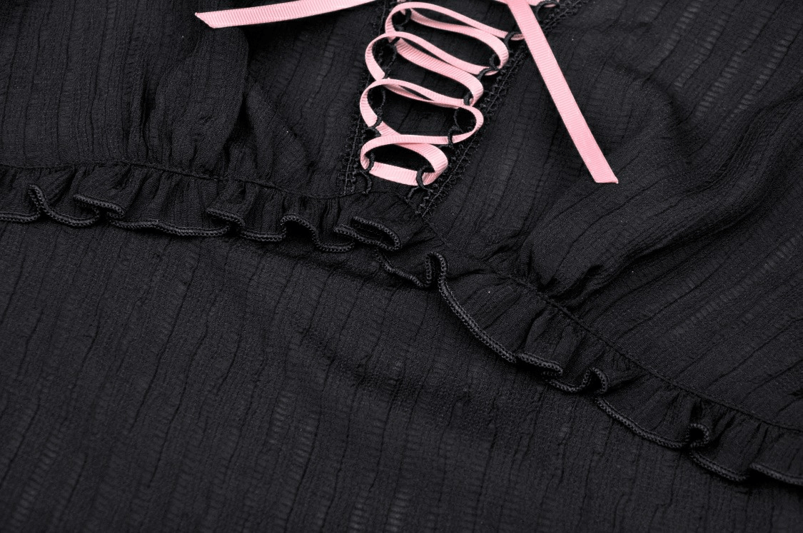 Close-up of black gothic off-the-shoulder top with pink ribbon detailing and ruffled edges.
