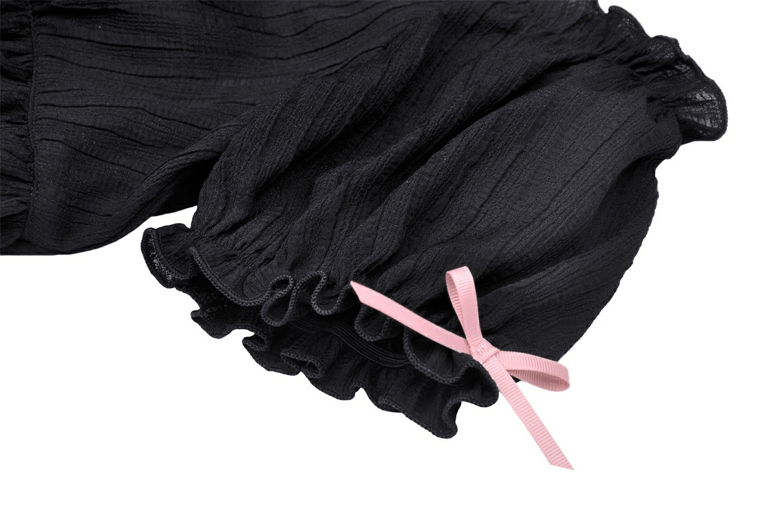 Close-up of black gothic top with pink ribbon detail, showcasing ruffled sleeves for a dark romantic style.