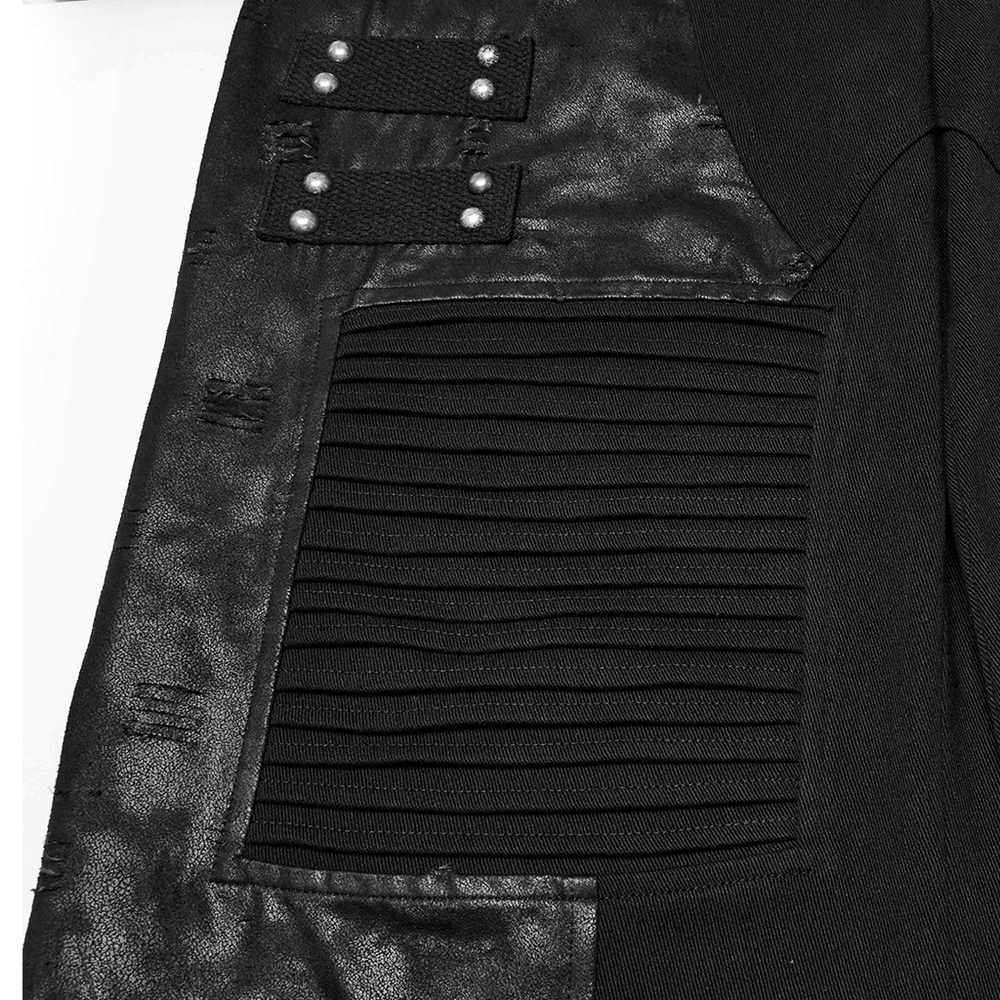 Close-up of black gothic pants featuring pleated panels and rivet details, showcasing edgy alternative fashion style.