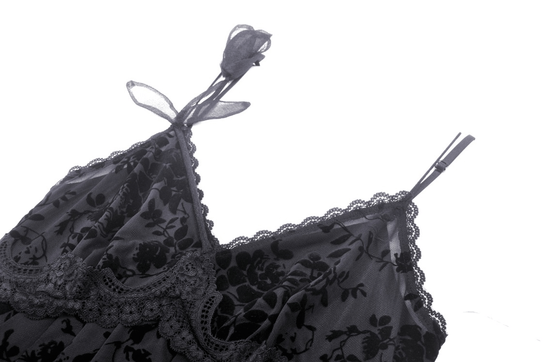 Black lace detailing with floral patterns on a delicate dress strap, embodying gothic elegance.