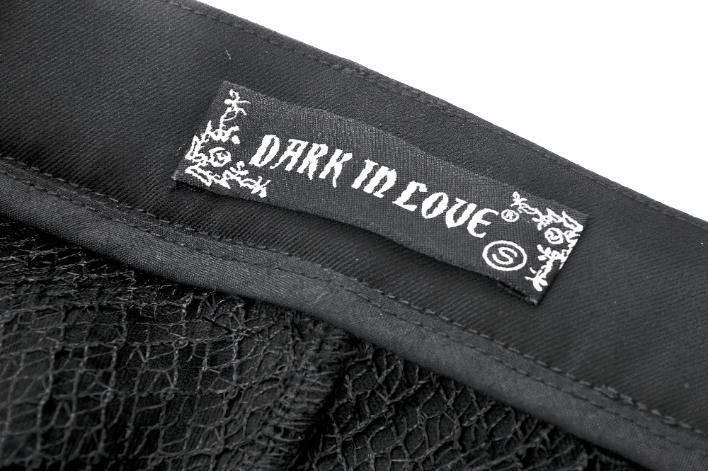Close-up of the 'Dark in Love' label on black gothic shorts, showcasing edgy style and unique fashion brand.
