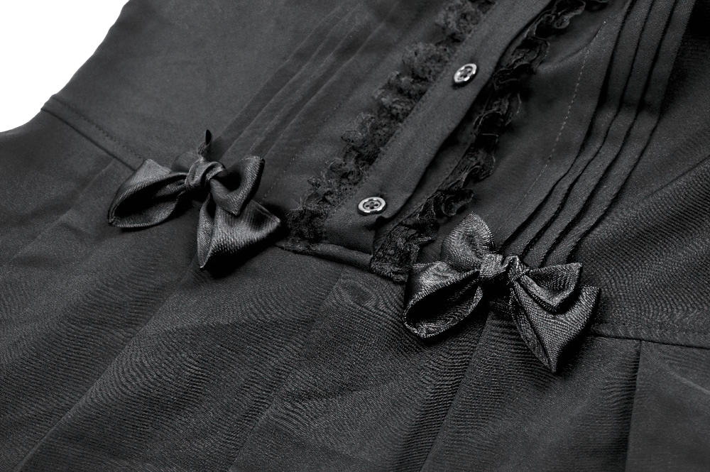 Close-up of black gothic sleeveless dress with pleats, lace trim, and satin bows accenting the waist.