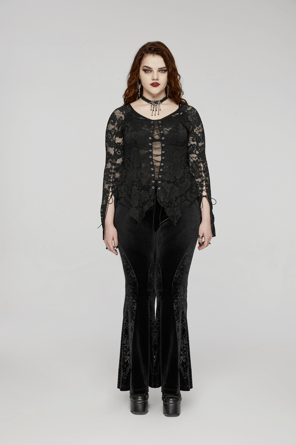 Model wearing black gothic velvet flared pants with embossed detailing and elegant lace top.