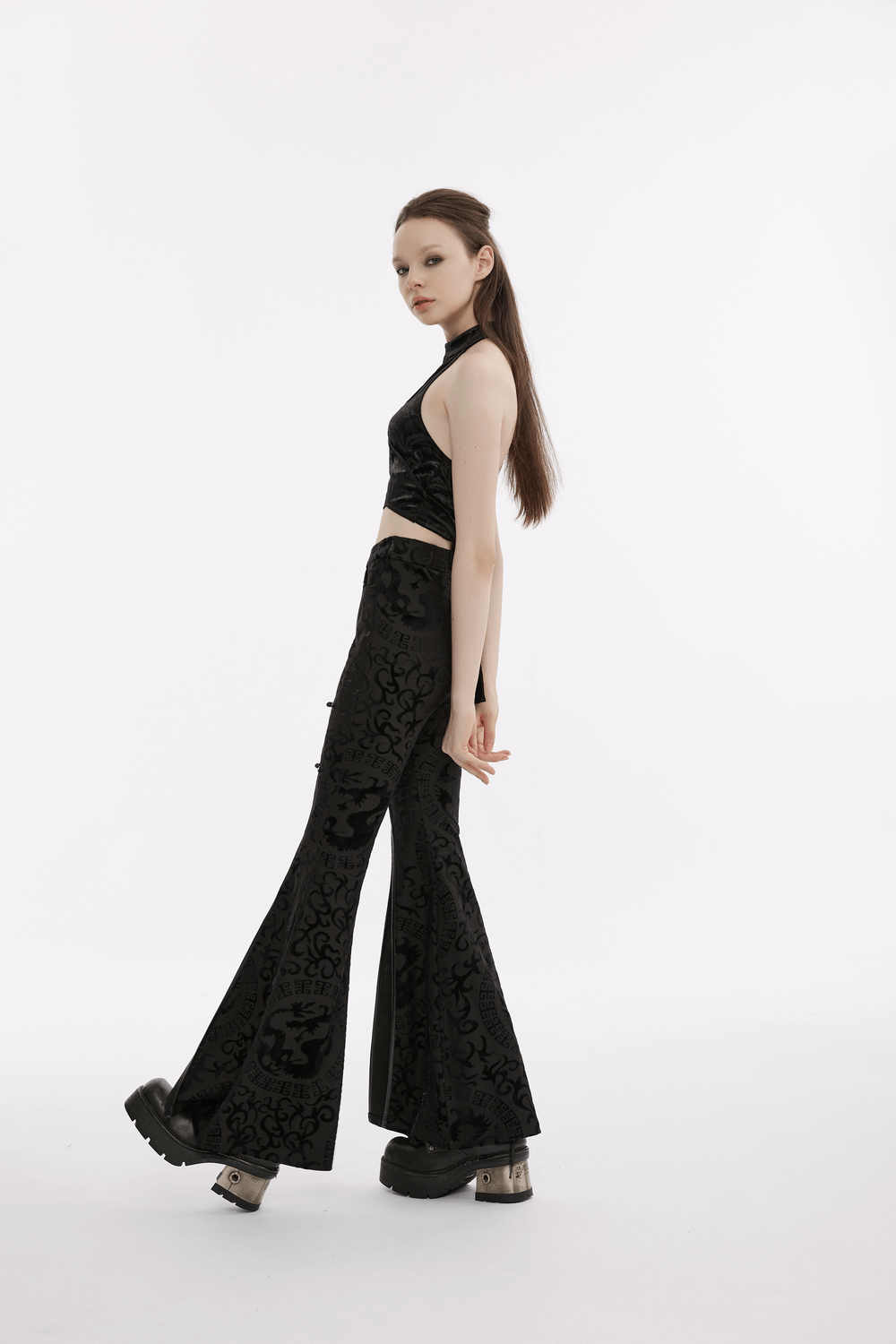 Model in a black gothic velvet halter tank top showcasing V-cut back and flared pants with intricate detailing.