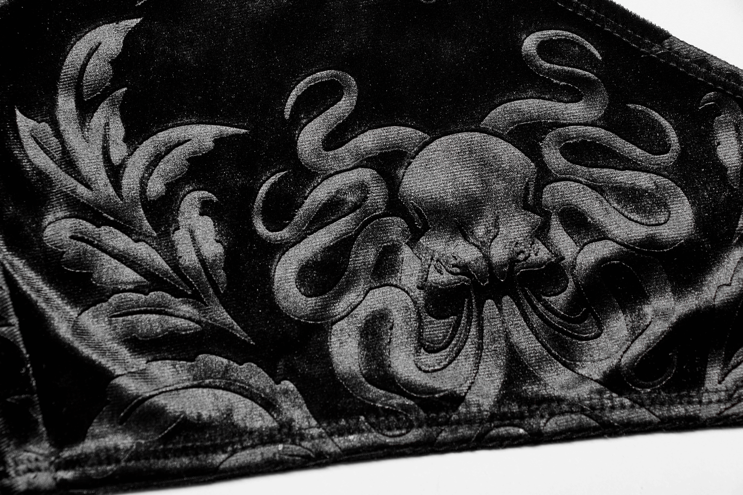 Close-up of black velvet featuring an intricate embossed octopus design with elegant floral elements.