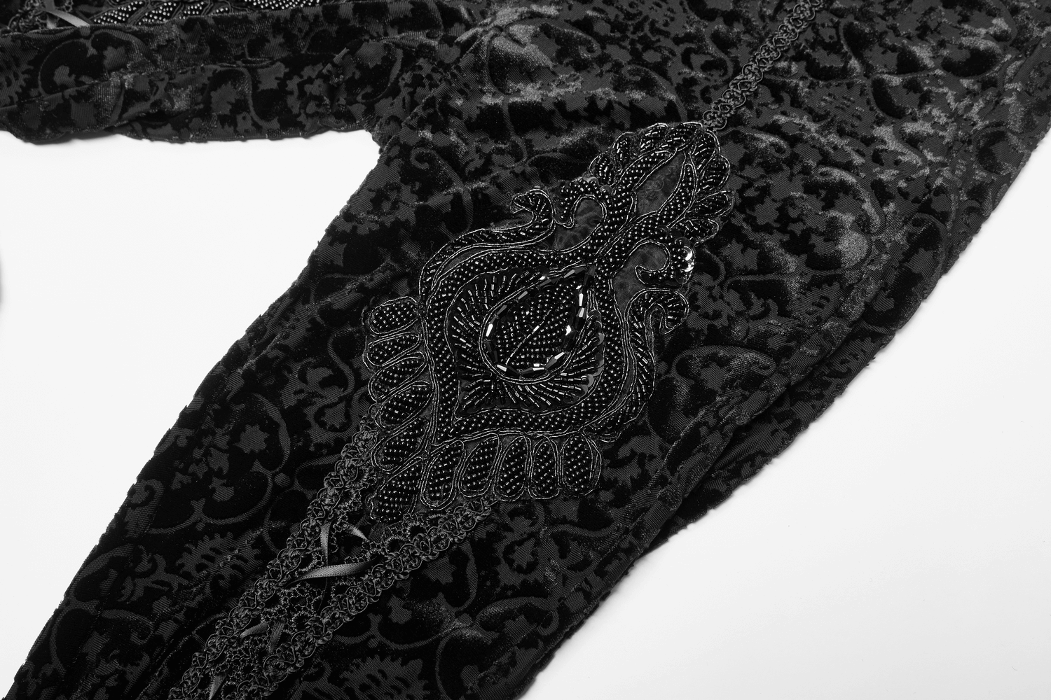 Close-up of black gothic velvet leggings with floral lace and intricate beadwork detail.