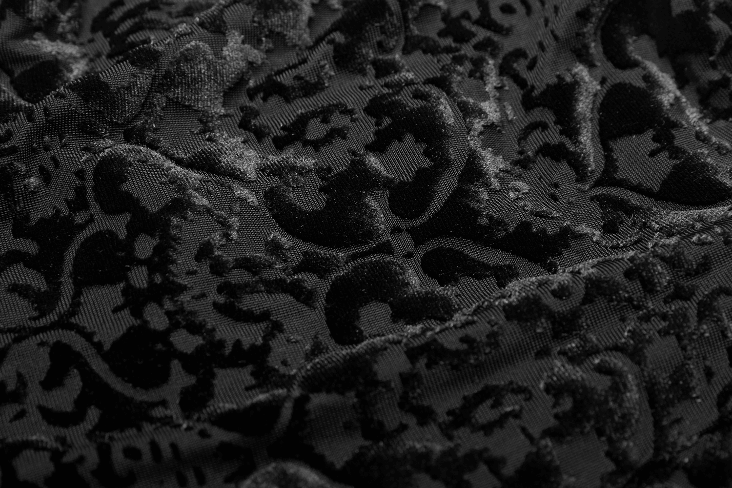 Close-up of black gothic velvet fabric featuring an elegant floral burnout design.