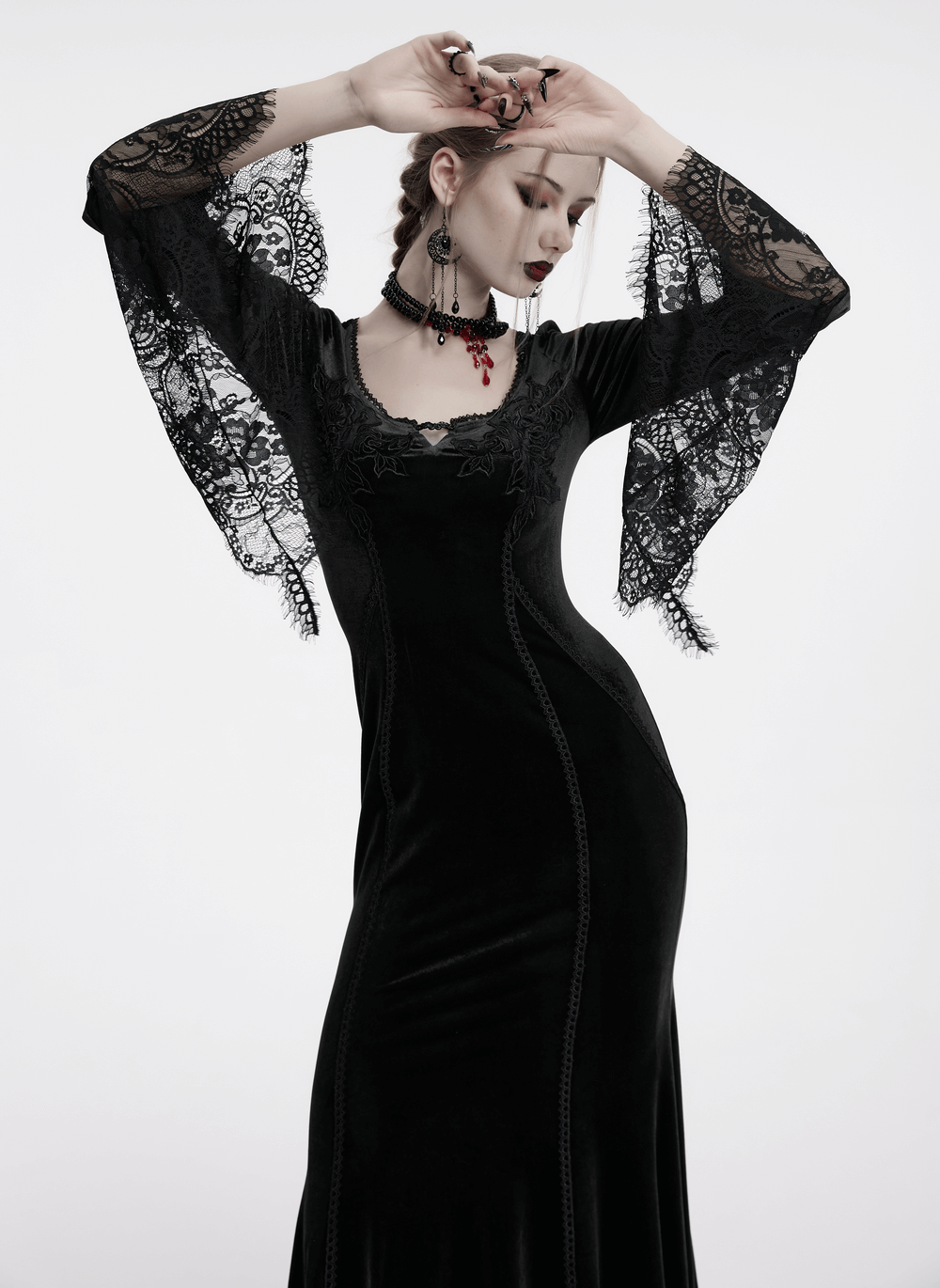 Elegant black gothic velvet maxi dress with lace sleeves and rose details, showcasing flowing movement and a corset back.