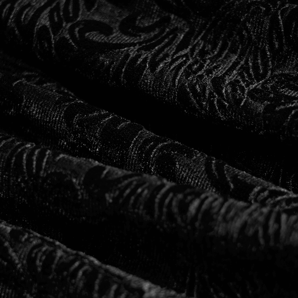 Close-up of luxurious black gothic velvet fabric with intricate shadow flower patterns.