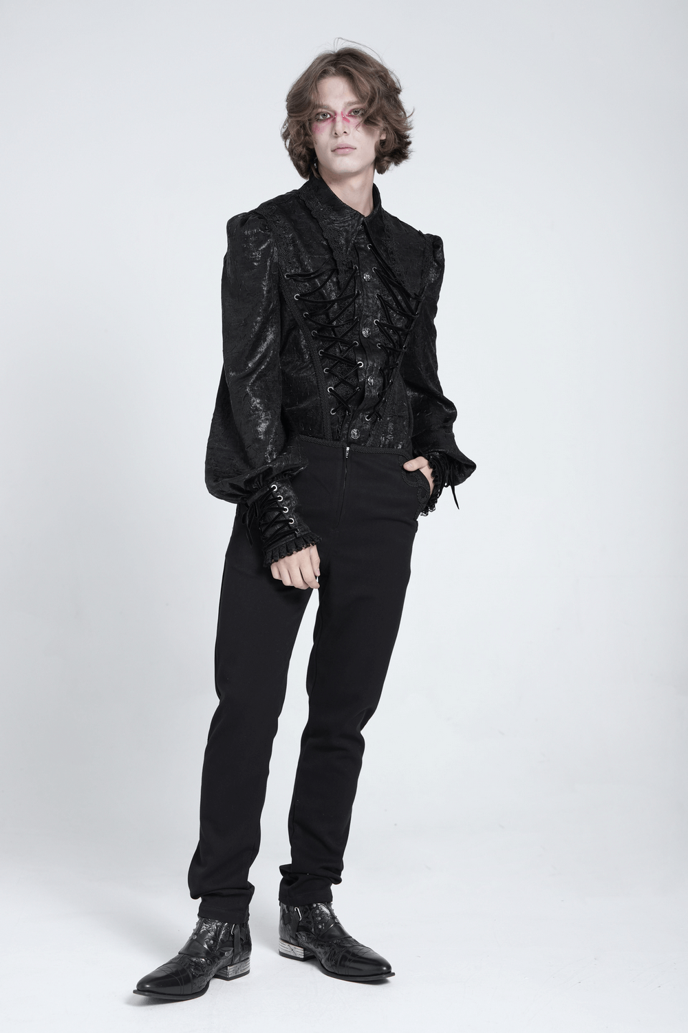 Model wearing a black Gothic Victorian lace-up shirt with puff sleeves and fitted pants, showcasing a dramatic alternative fashion look.