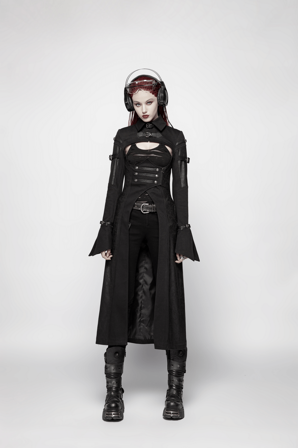 Edgy model in black punk outfit with a long coat, showcasing stylish music headphones and a fierce look.