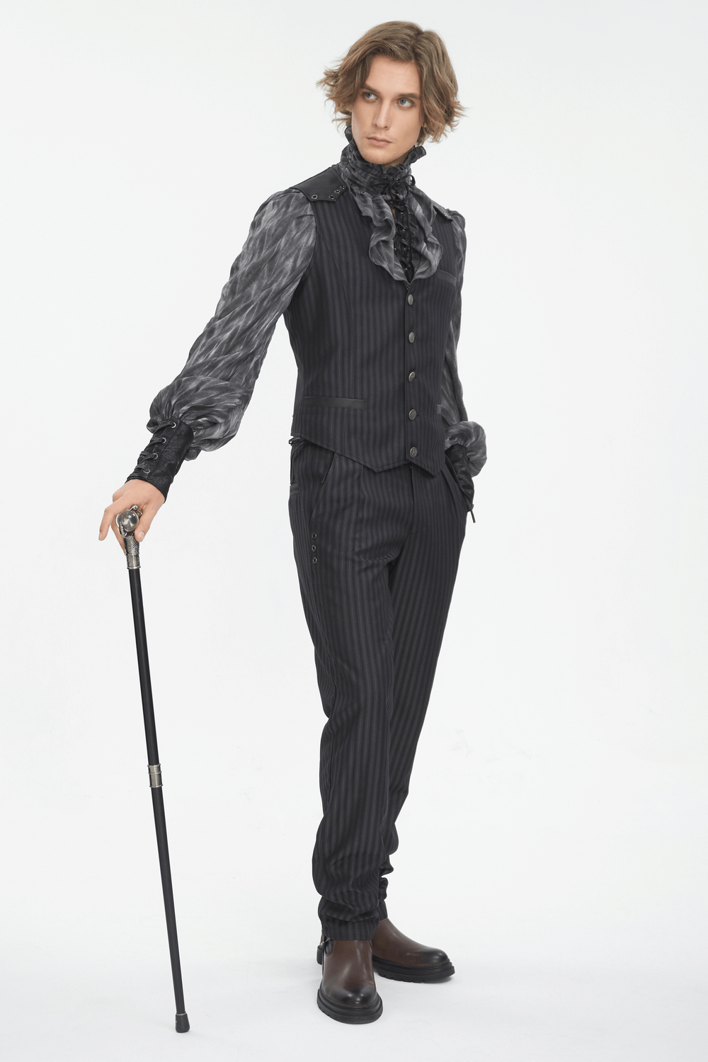 Stylish man in a black striped suit with a ruffled shirt, holding a cane, posing confidently on a white background.
