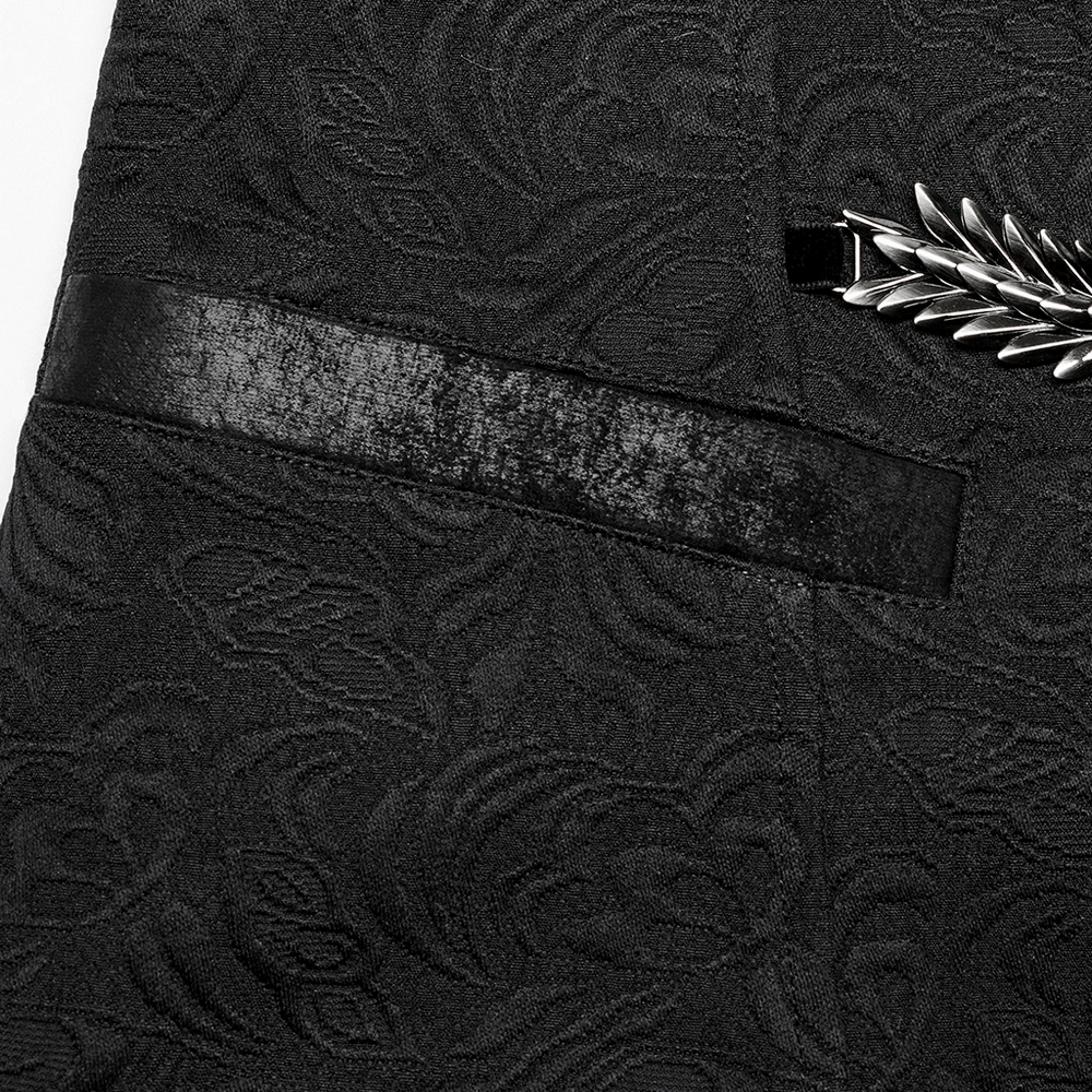 Close-up of the intricate black jacquard fabric and pocket of a gothic dragon scale waistcoat with a silver decorative detail.