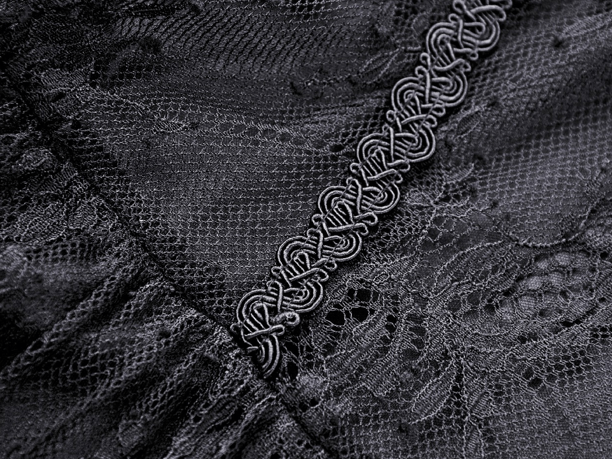 Close-up of intricate black lace fabric with decorative trim, showcasing elegance and gothic style details.