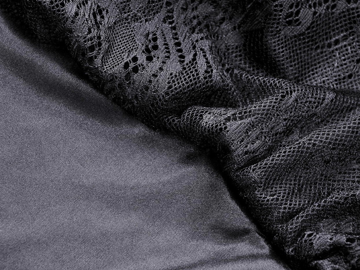 Close-up of elegant black lace fabric combined with smooth satin, perfect for a gothic dress design.