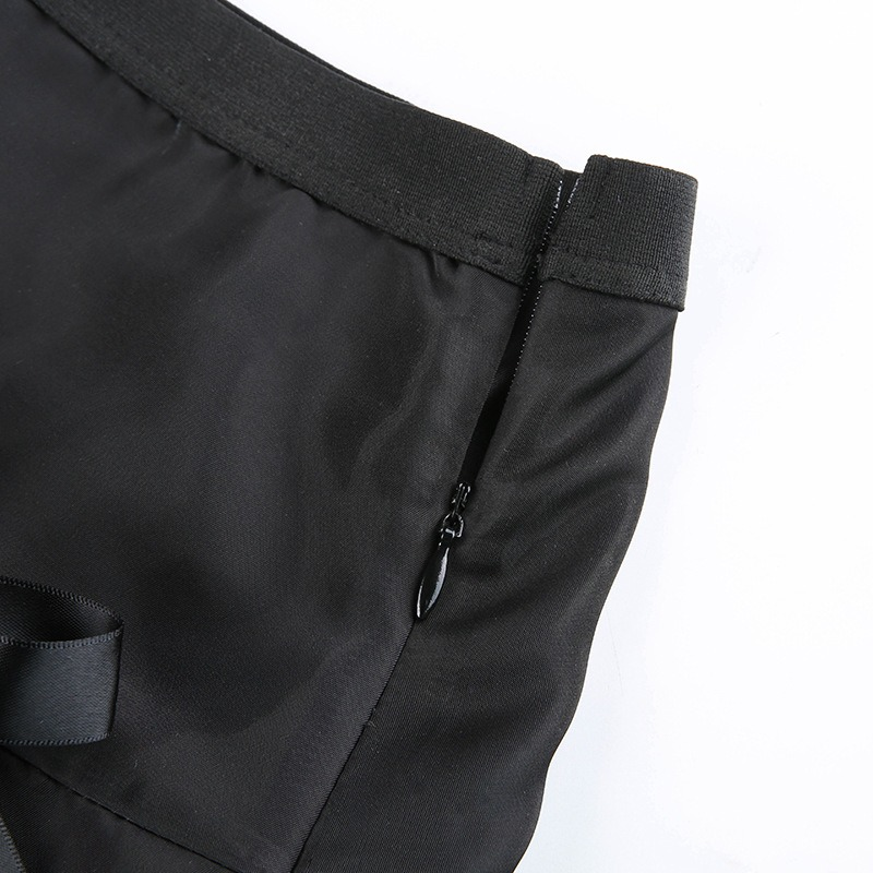 Close-up of the zipper and waistband on a black lace gothic mini skirt, showcasing pleated design and elegant bows.