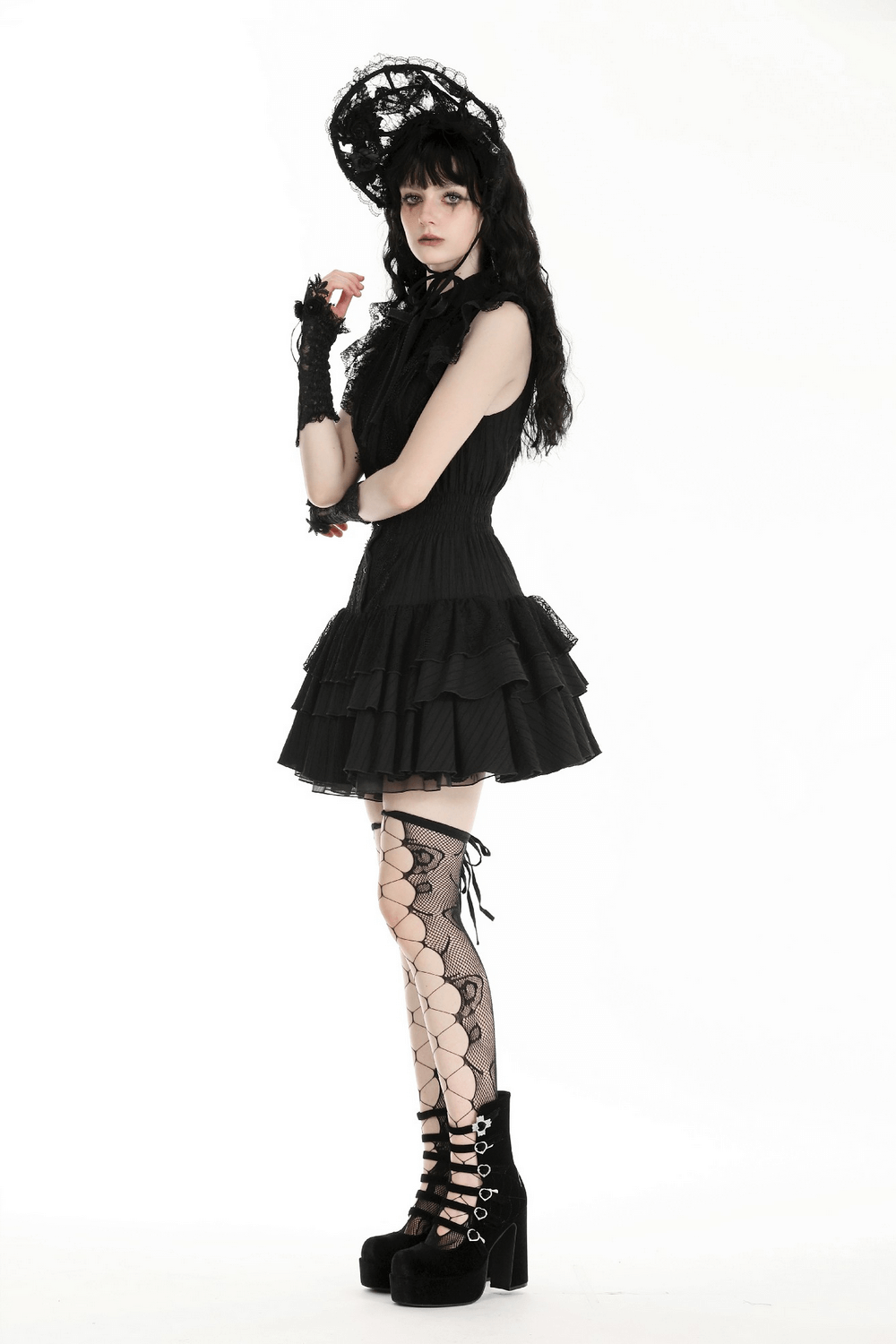 Gothic black lace ruffled dress with hat, gloves, and fishnet stockings, showcasing elegant gothic style.