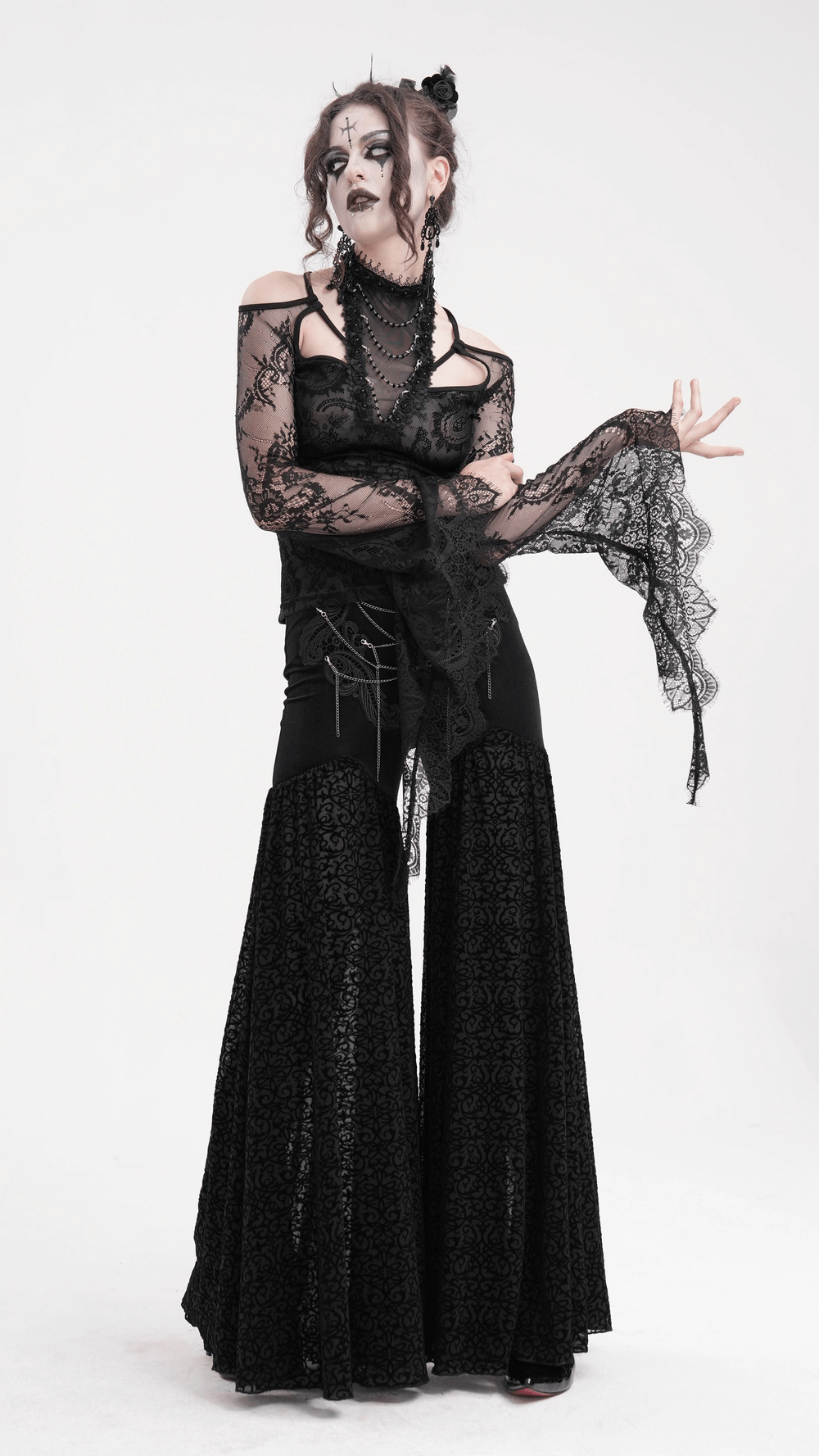 Model wearing a black lace gothic top with bell sleeves and neck chains, showcasing an elegant Victorian-inspired look.