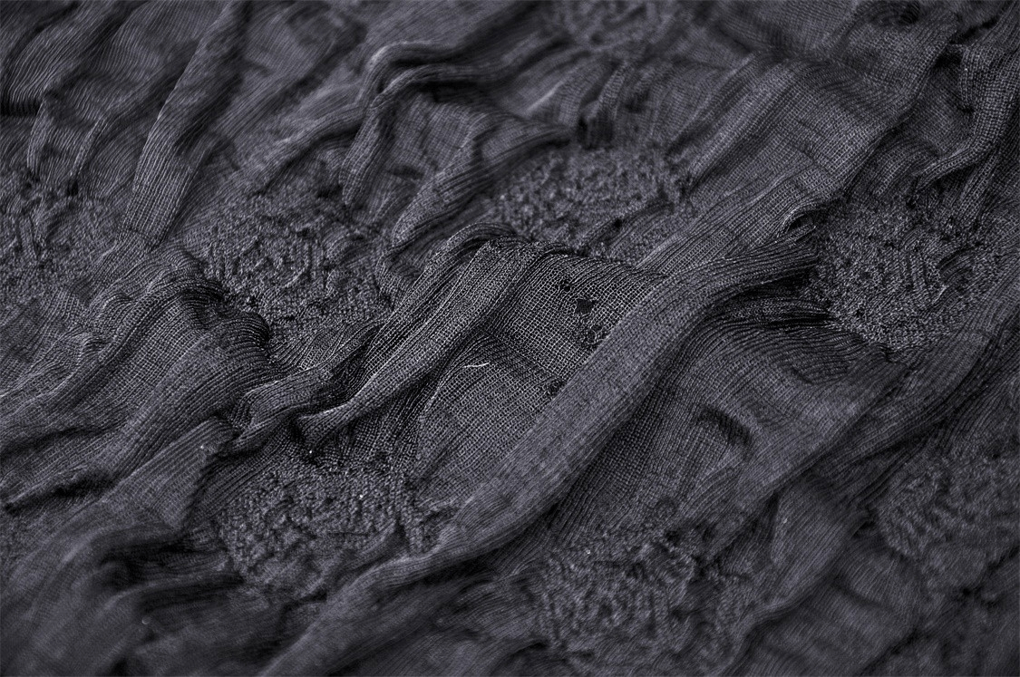 Close-up of intricate black lace fabric showcasing ruffled texture for gothic high-low dress design.