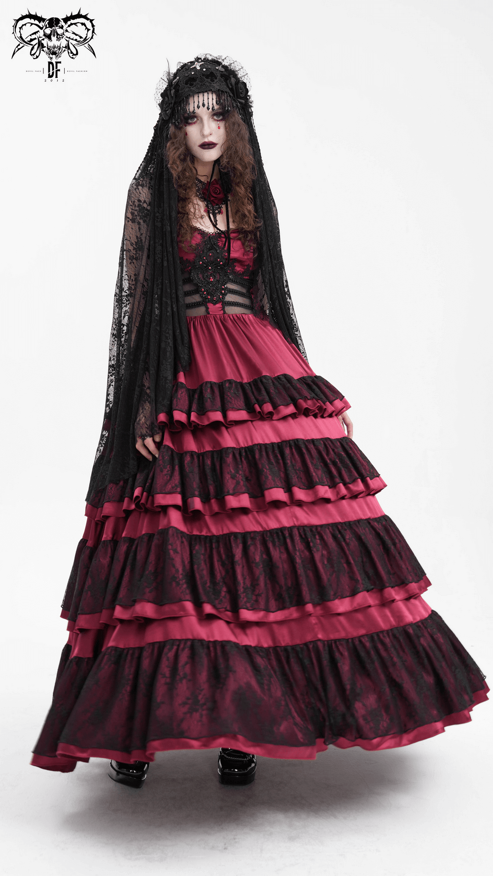Gothic woman in black lace veil and layered red and black dress, embodying dark fashion elegance.