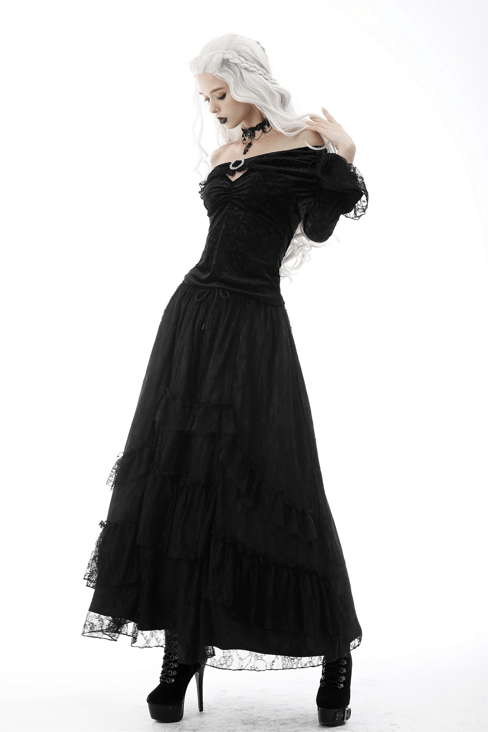 Victorian-inspired black lace off-shoulder top with brooch detail, paired with a flowing maxi skirt and elegant black boots.