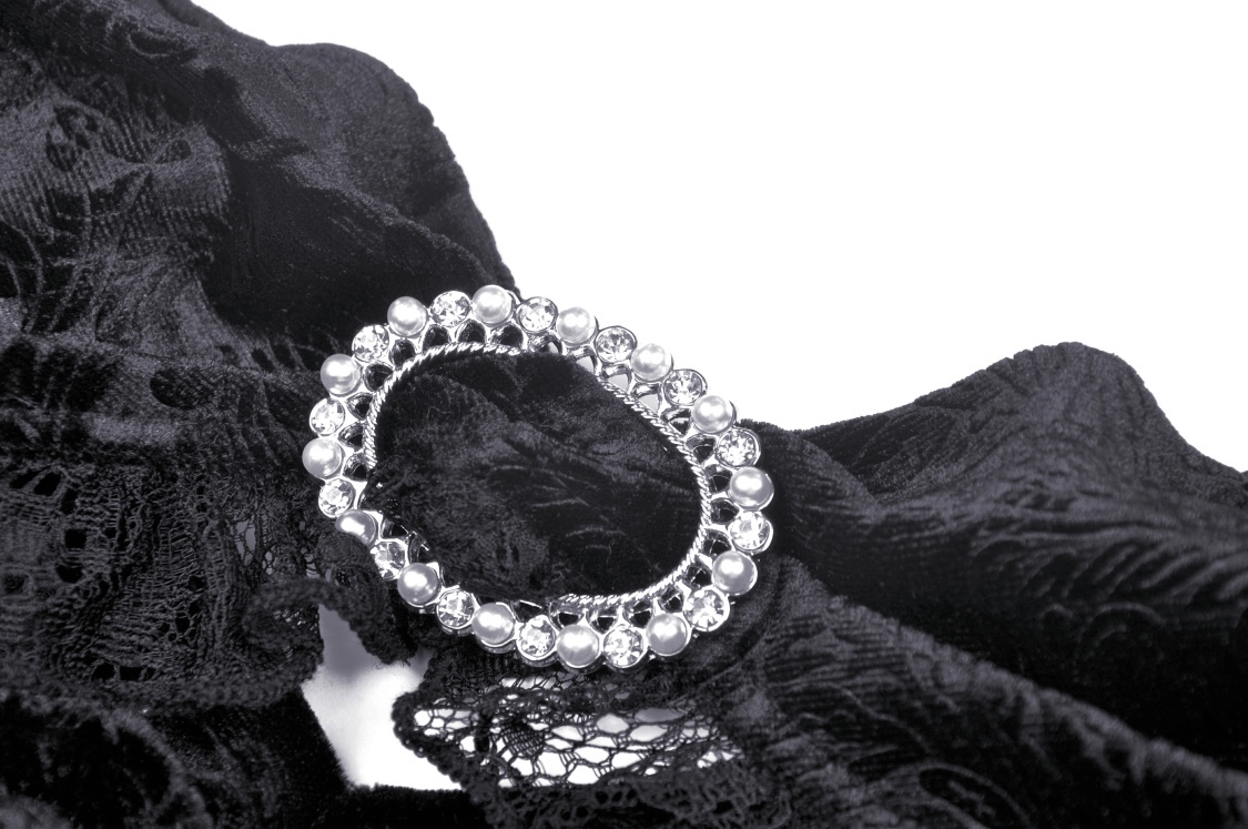 Elegant silver brooch centered on exquisite black lace fabric, perfect for a gothic-inspired design.