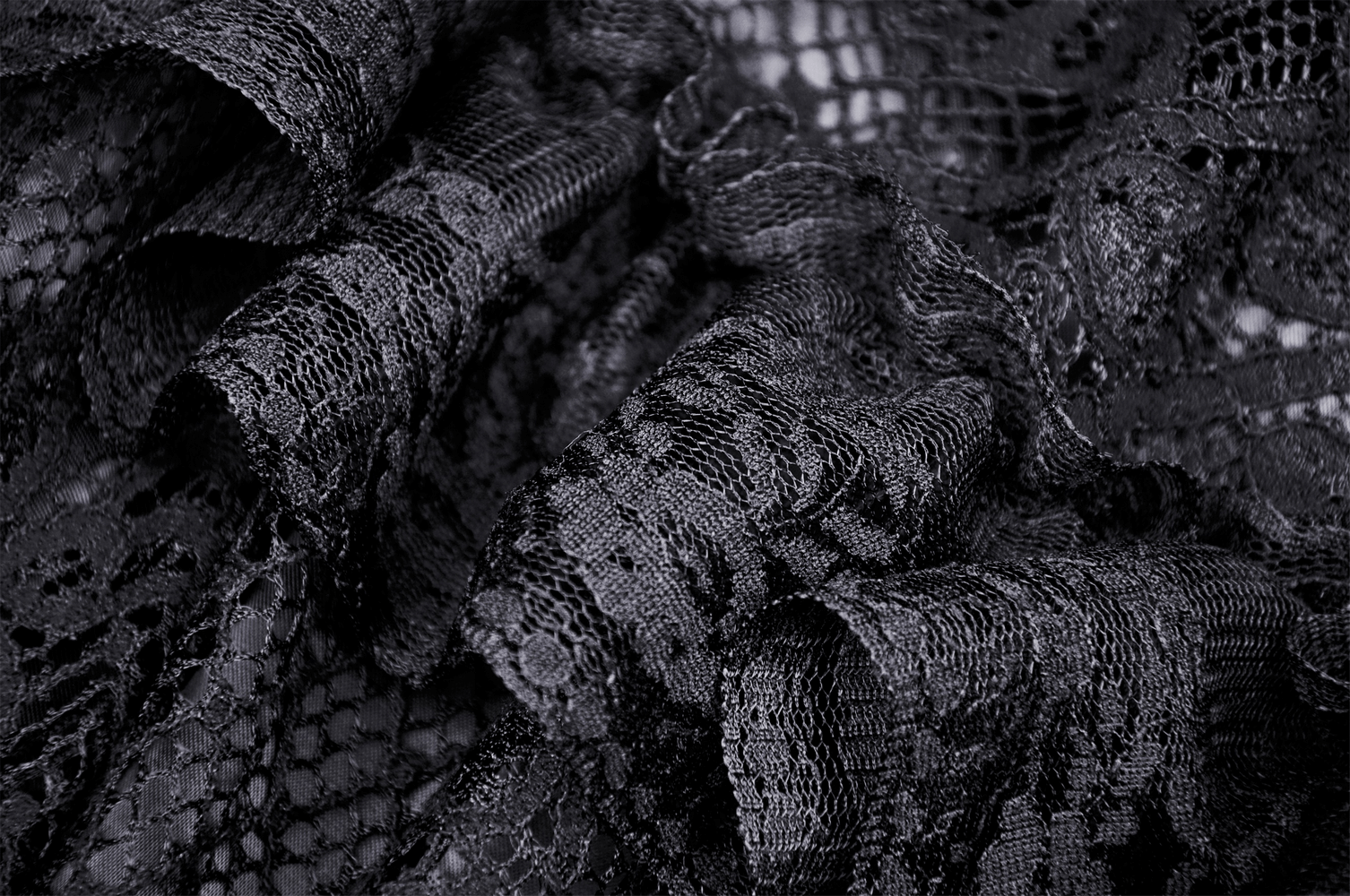 Close-up of black lace fabric with intricate patterns, perfect for a tiered skirt with frills.