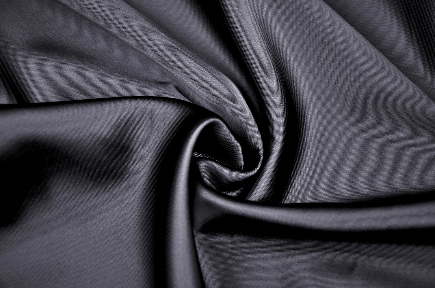 Close-up of luxurious black fabric, showcasing a smooth, silky texture ideal for elegant clothing.