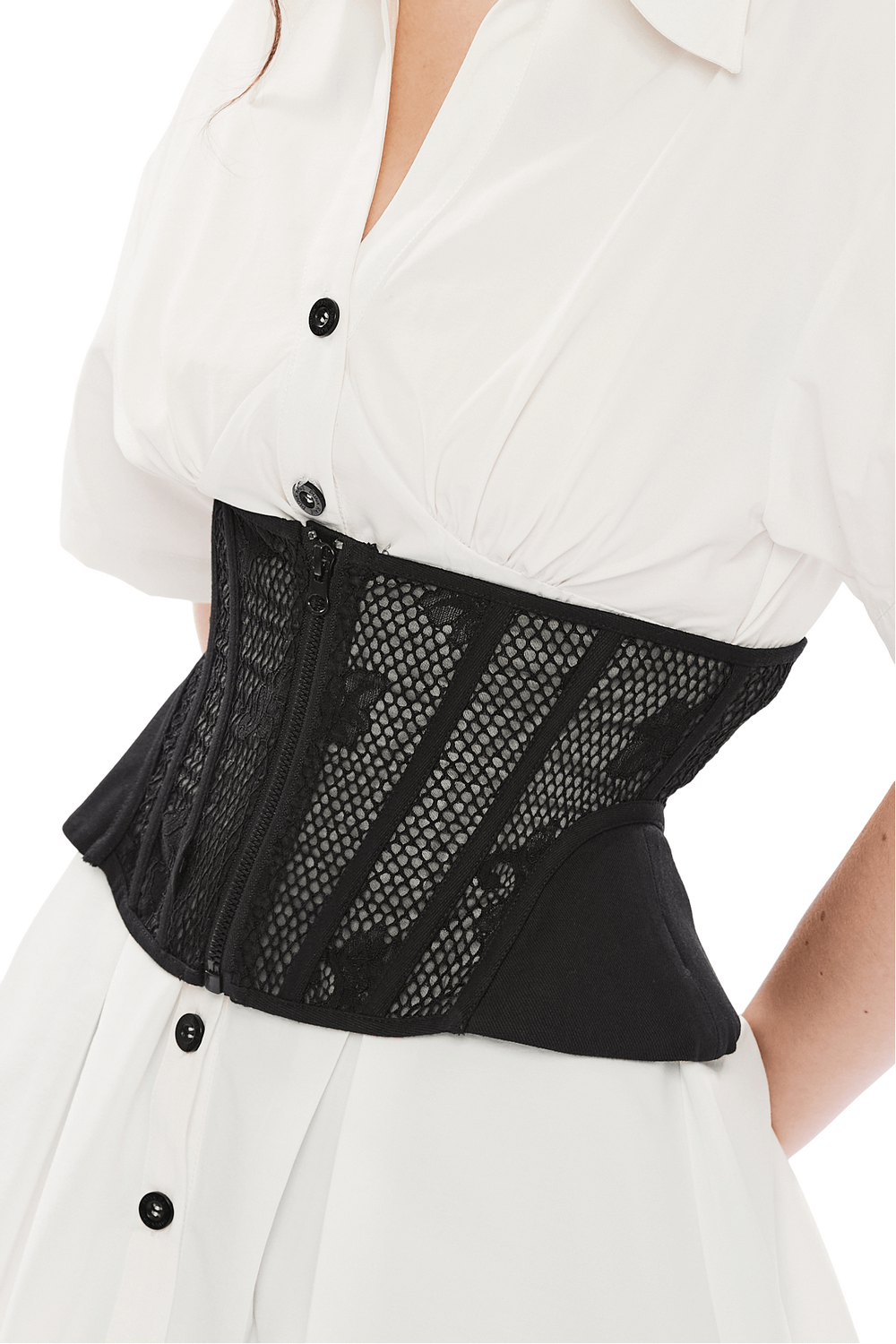 Black lace-up cincher corset with mesh panels worn over a white dress, showcasing sophisticated silhouette and structured design.