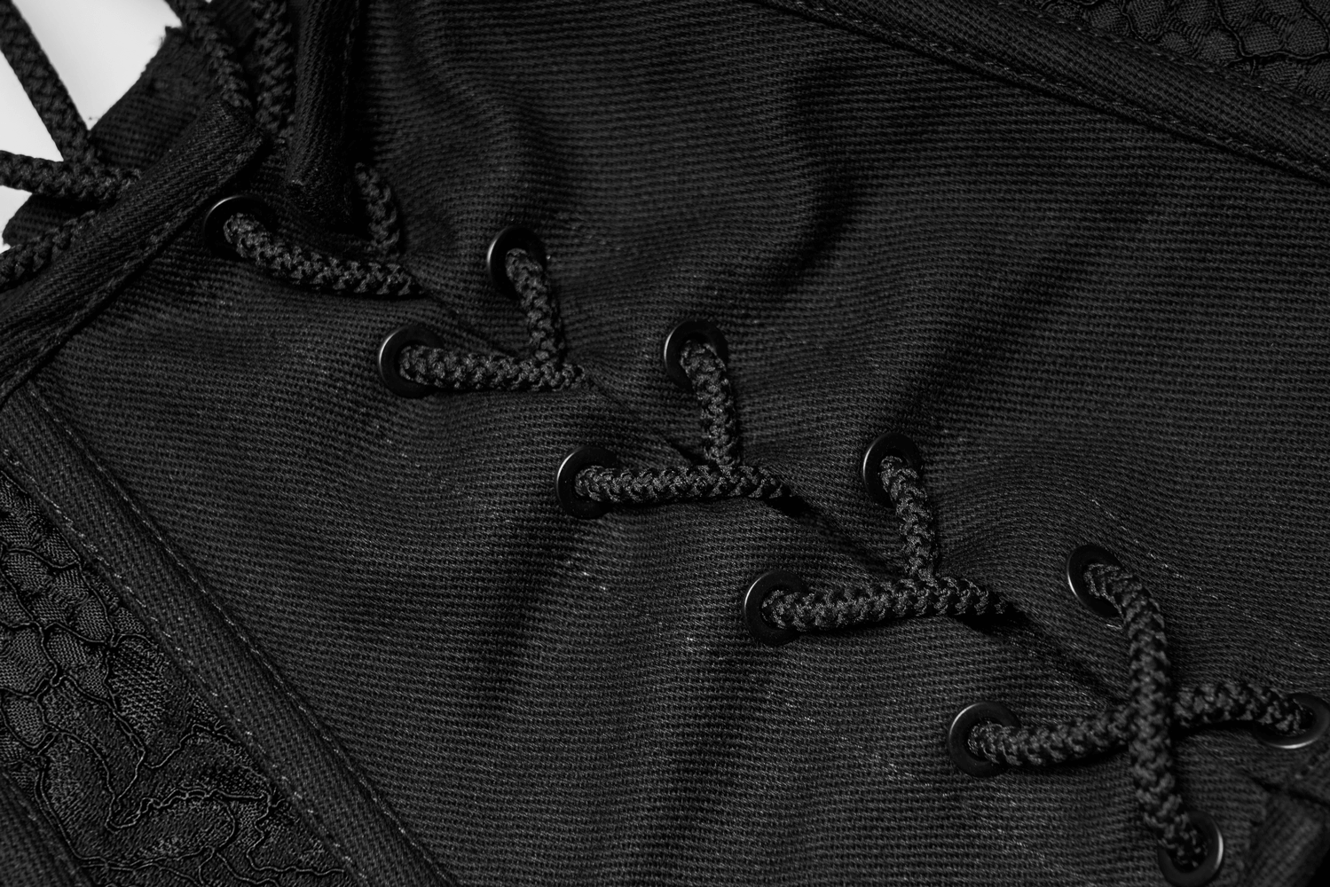 Close-up of black lace-up details on a cincher corset, showcasing elegant texture and sophisticated design.