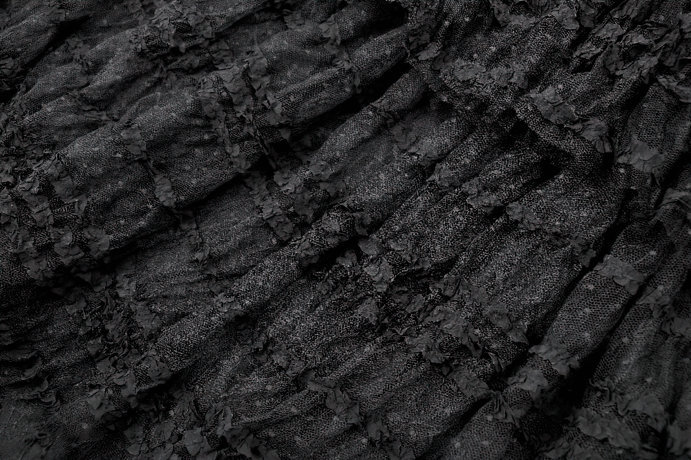 Close-up of textured black lace fabric, showcasing ruffled layers for a gothic maxi skirt.