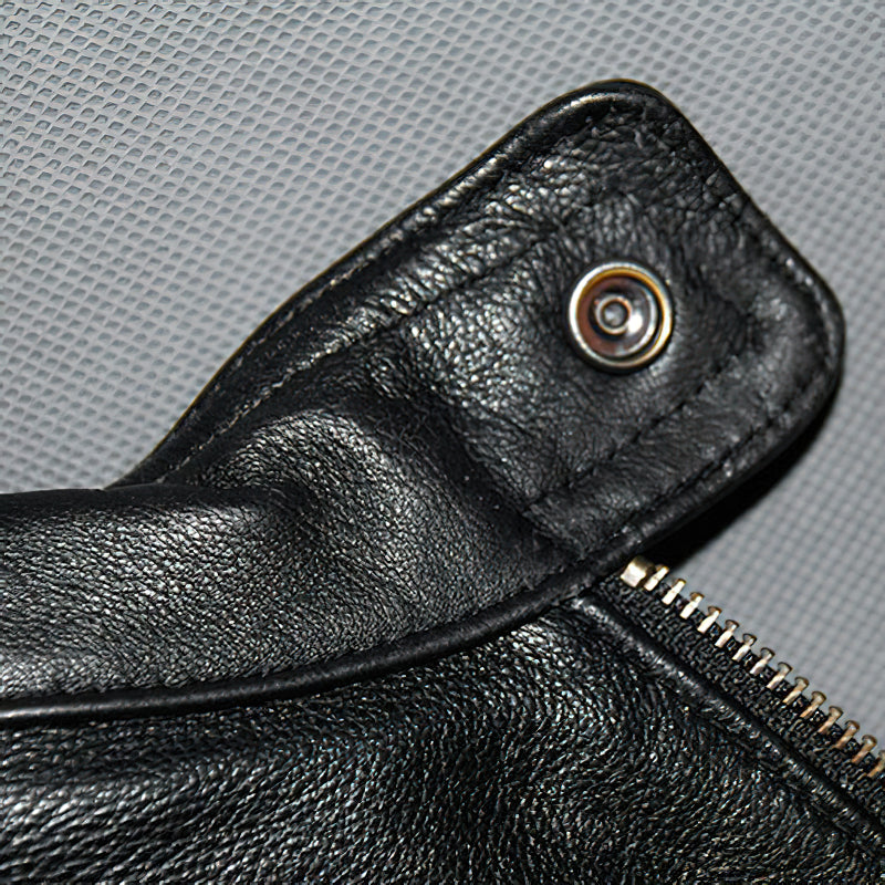 Close-up of the snap button and zipper detail on a black men's leather motorcycle jacket.