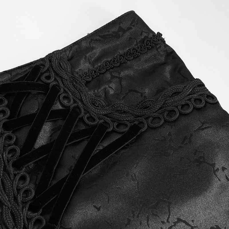Close-up of black gothic trousers featuring lace-up detail and unique vintage fabric texture.