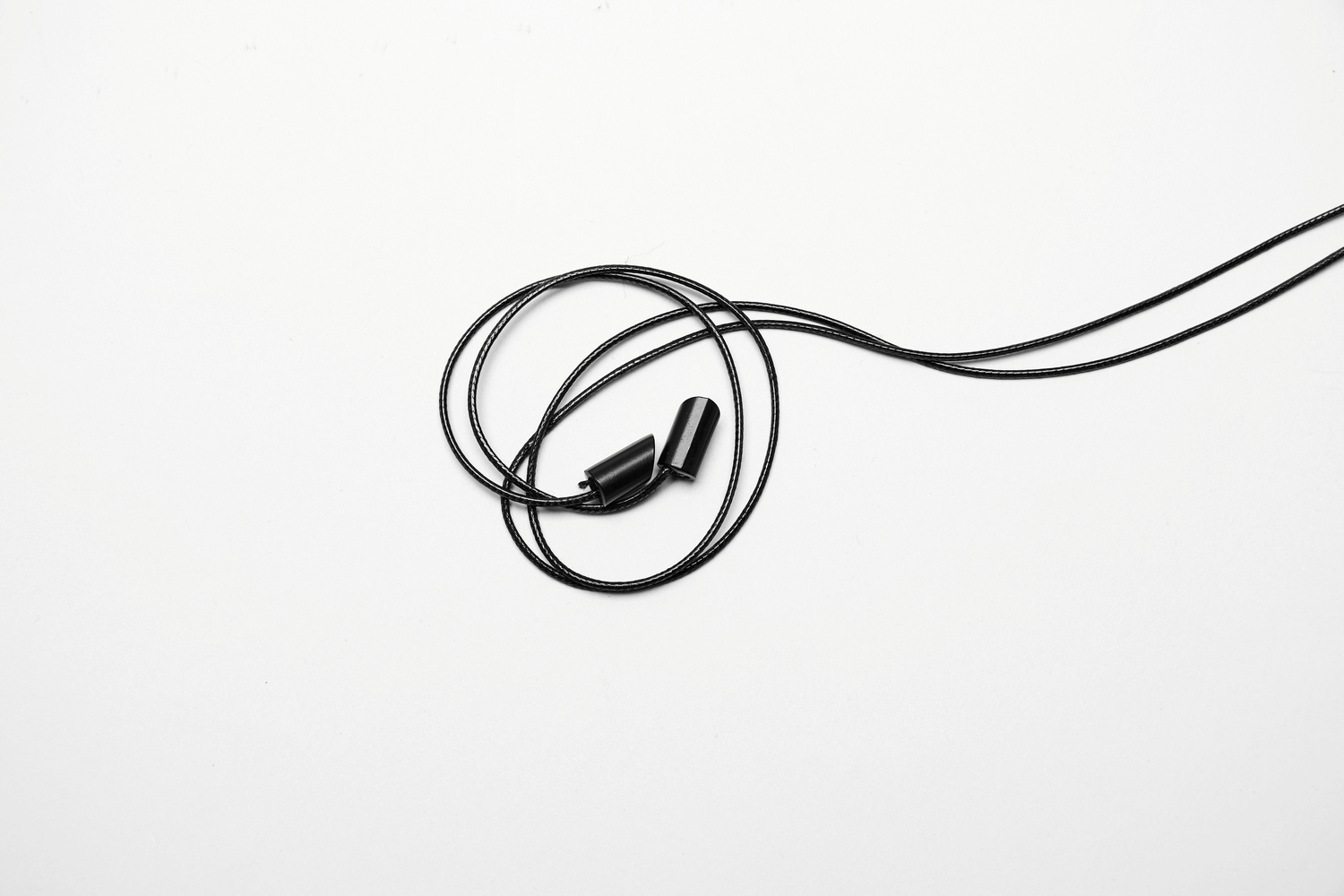 Black wired earphones tangled on a white background, perfect for music lovers and audiophiles.
