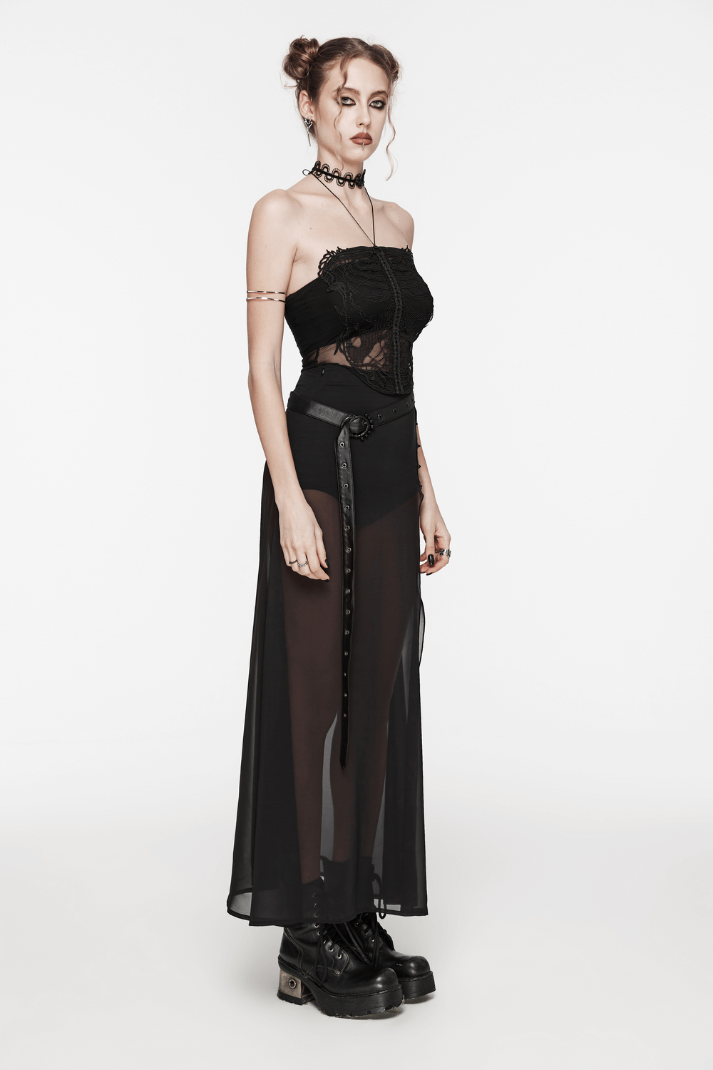 Model wearing a black mesh halter top with embroidered gothic skeleton and a sheer black skirt, styled with chunky boots.