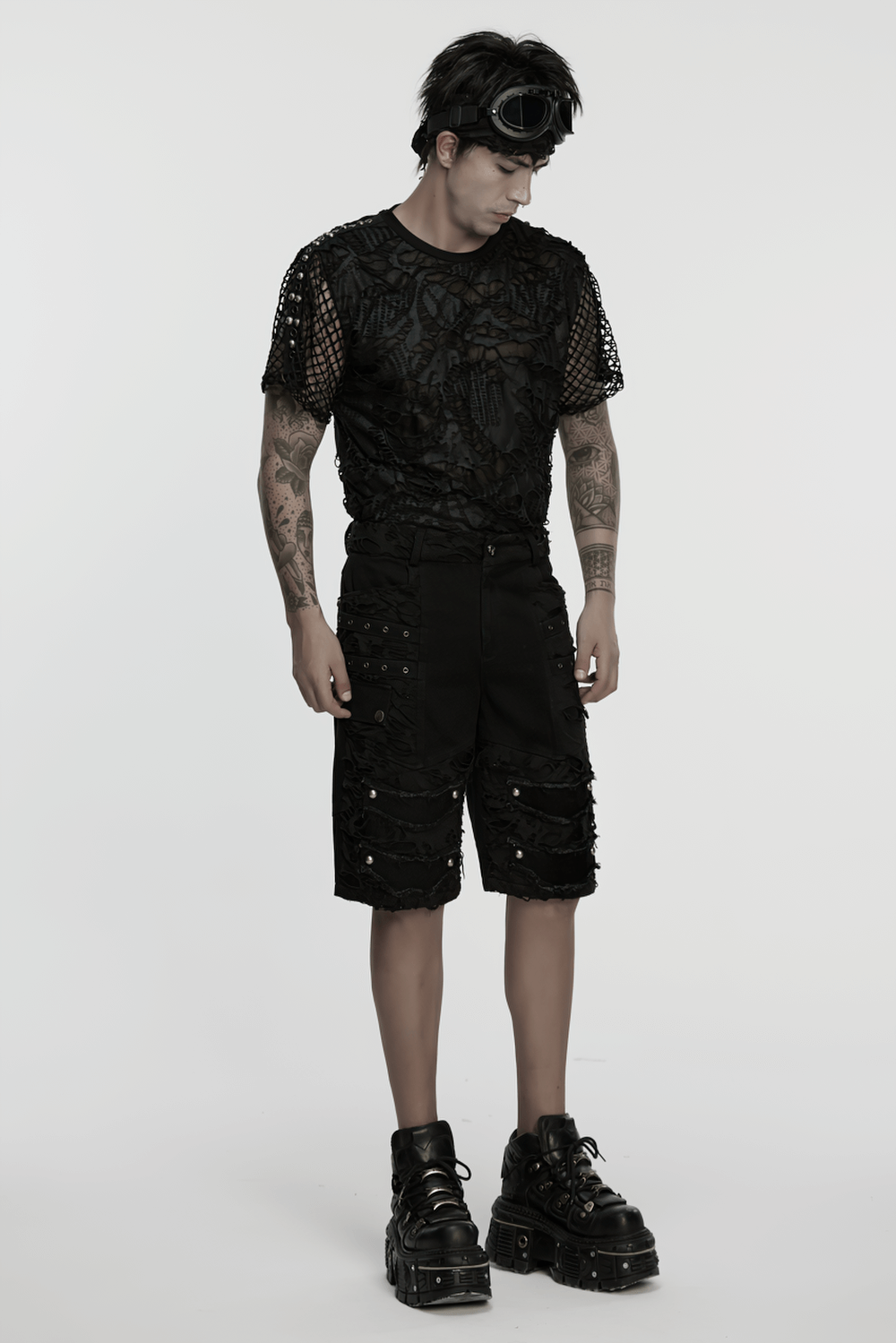 Stylish model in black punk denim shorts with tattered detail and bold platform shoes, showcasing alternative fashion.