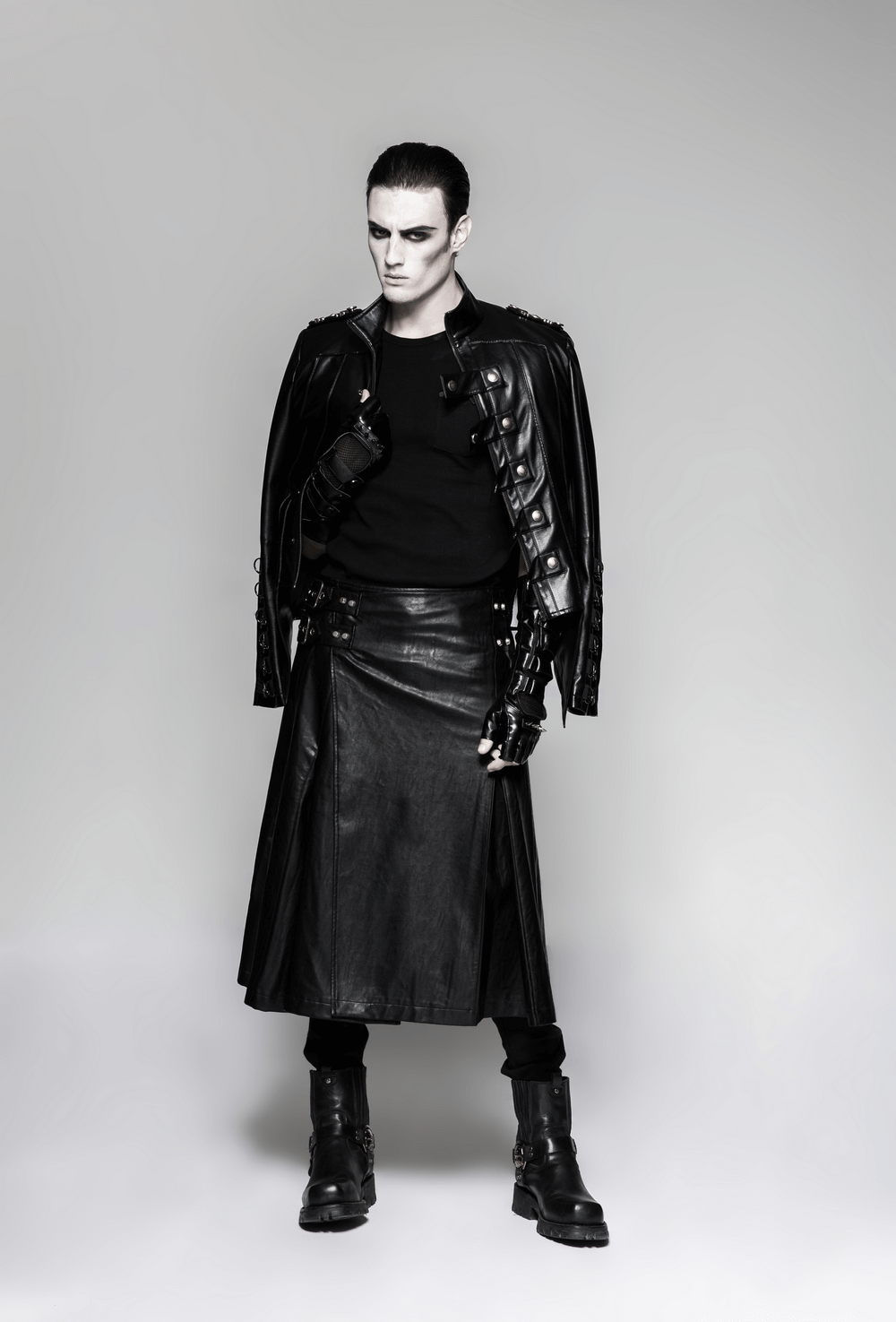 Stylish individual in black leather outfit showcasing punk fashion with spikes, gloves, and a daring leather skirt.