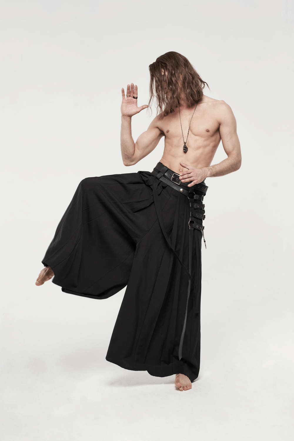 Black punk kimono wide leg pants with buckles, worn by a model striking a warrior pose.