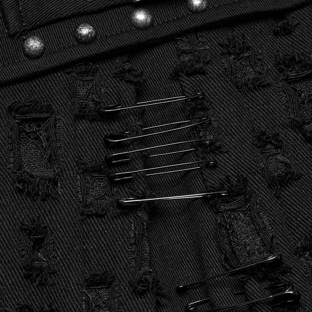 Close-up of black punk mini skirt showcasing metal studs and safety pins on distressed denim.