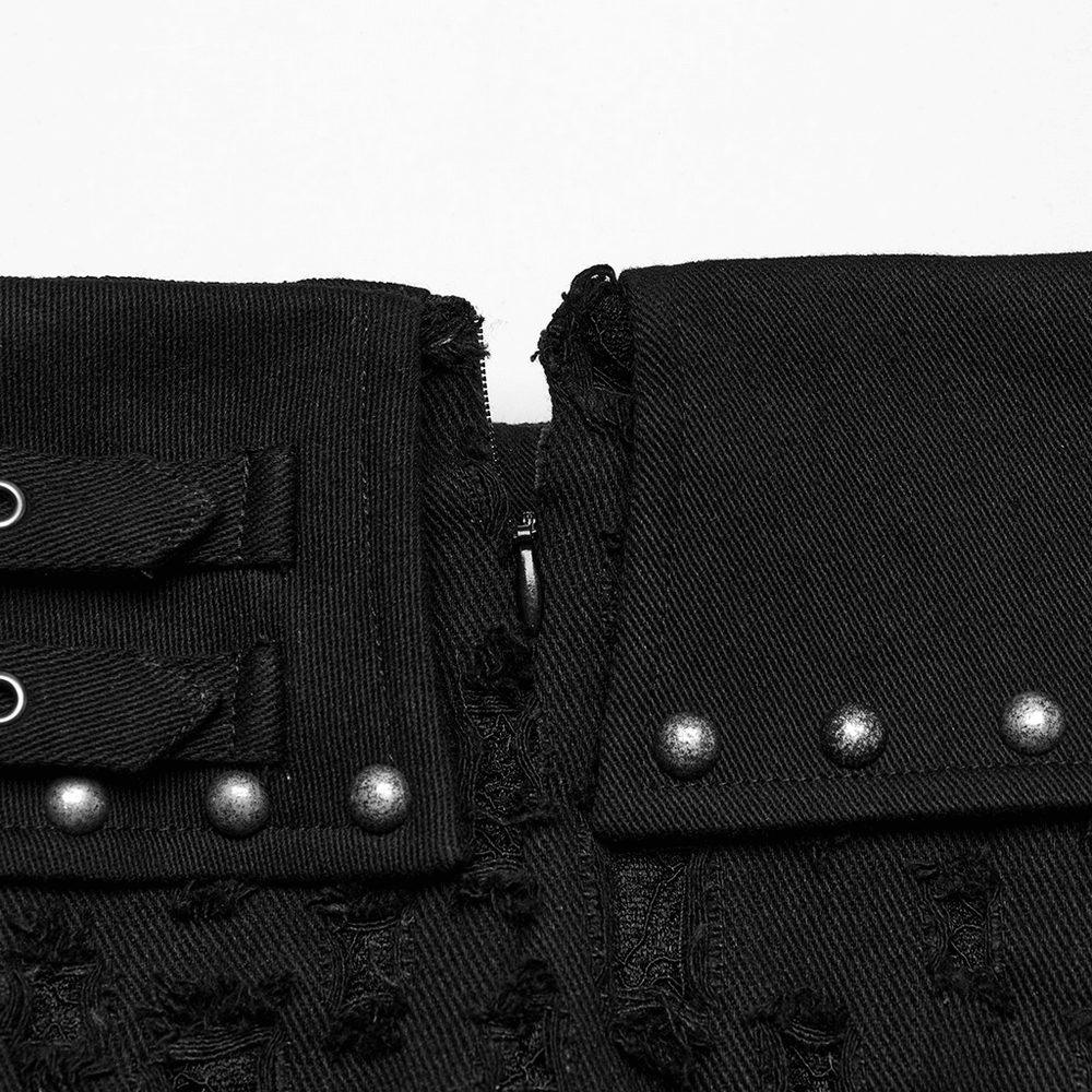 Close-up of black punk mini skirt with studs, safety pins, and edgy denim details.