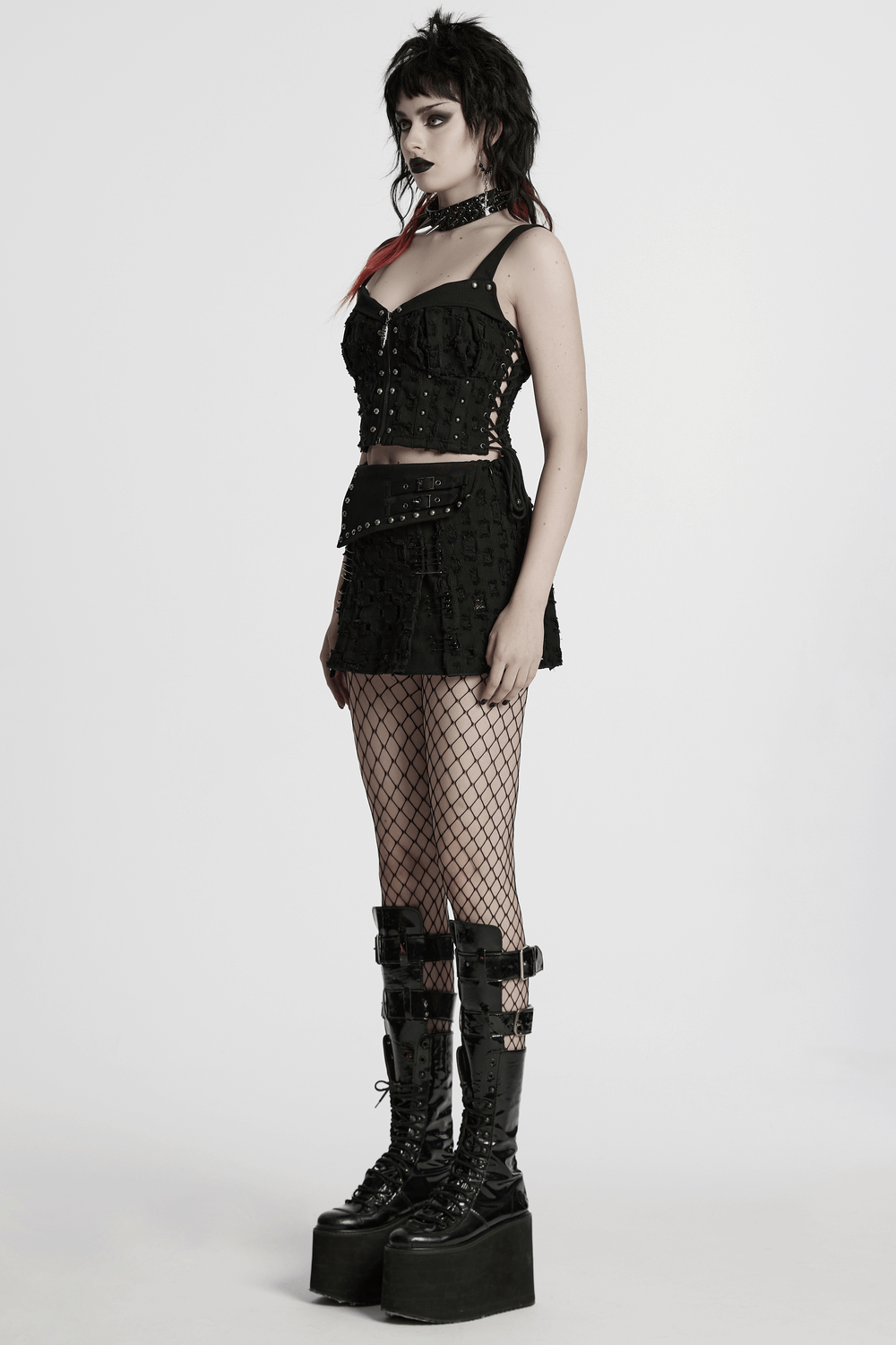 Model showcasing a black punk mini skirt with studs, fishnet tights, and chunky platform boots.