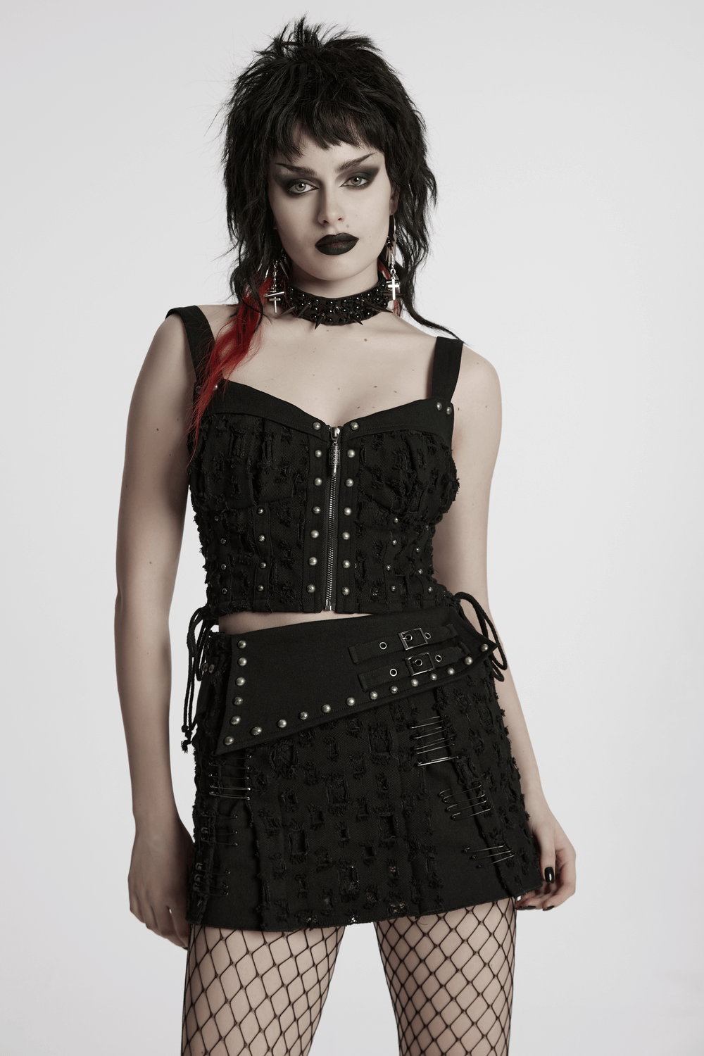 Model showcasing a black punk mini skirt with studs, safety pins, and edgy corset top for a rebellious look.