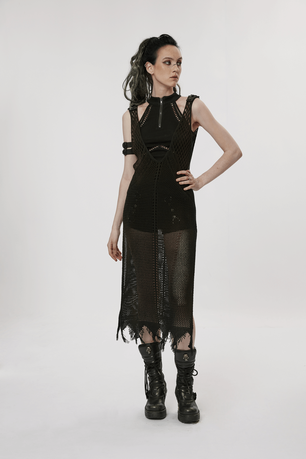 Model showcasing a black punk rave outfit, featuring a netted dress and bold combat boots for a fierce look.