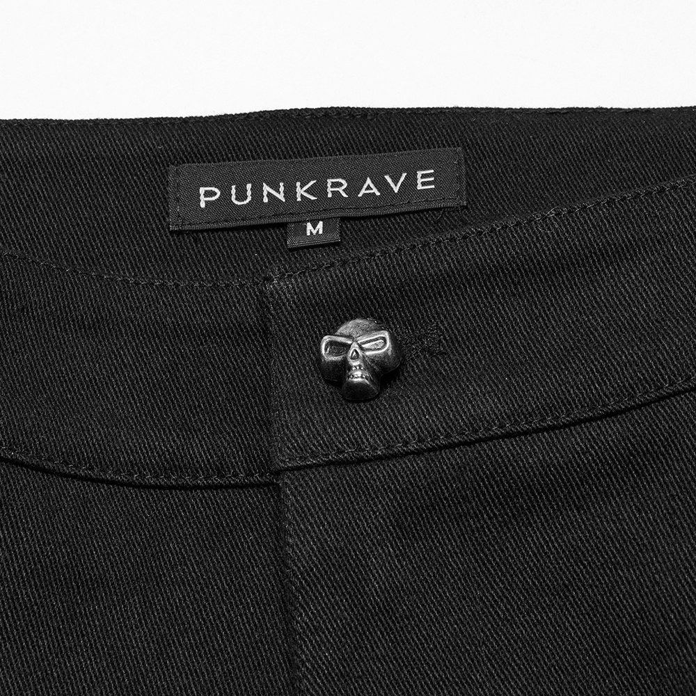 Close-up of black punk shorts with skull rivet and PUNK RAVE label, showcasing edgy design details.